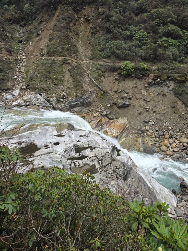 Trekkers crossing a suspension bridge over a river on the Arun Valley Trek in Nepal